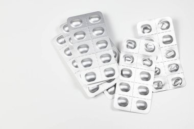 Bazı kullanılmış ilaç paketleri, tıbbi ilaçlar ve gümüş renkli parlak paketler beyaz arka planda izole edilmiş..