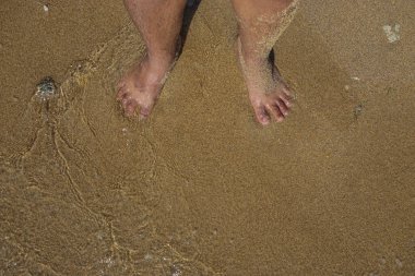 Sahilde duran bir çift ayak.