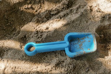 Plajın beyaz kumlarında plastik kürek. Sahildeki çocuk aktiviteleri için resim.