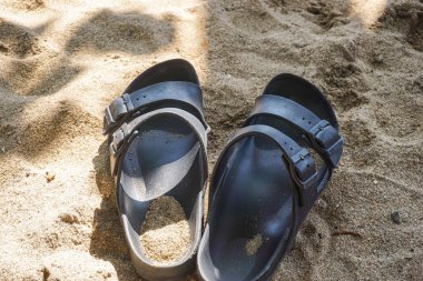 Sahilin beyaz kumlarında bir çift sandalet..