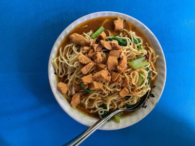 Üzerine doğranmış tavuk ve ıspanak sebzesi konmuş tavuk eriştesi. Cakarta 'nın tipik Tavuk Eriştesi. Adı 