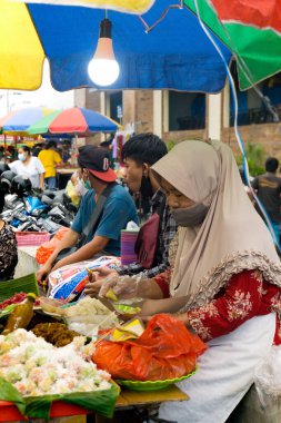 Denpasar, Bali, Endonezya (19 Haziran 2021): Denpasar geleneksel pazarı. Yaşlı kadın tüccar geleneksel pazarda mallarını bekliyor.