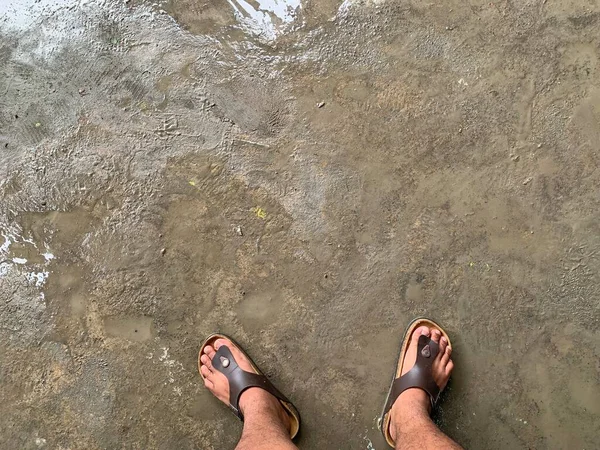 A pair of legs standing on a wet road after the rain