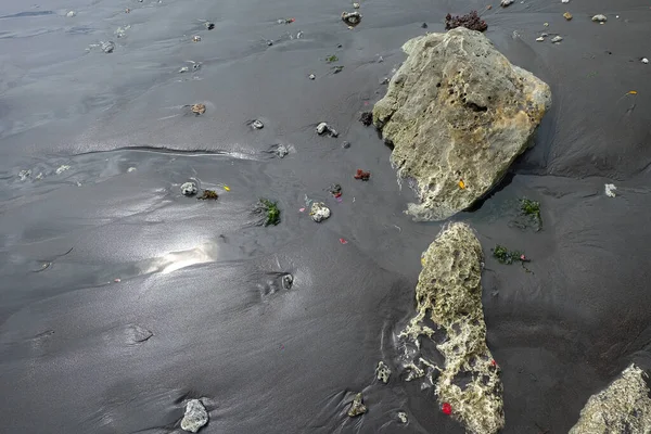 Black sand and rocks on the beach. Black sand background. Black sand texture