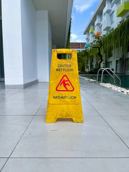 A wet floor sign placed next to the pool. Reads \
