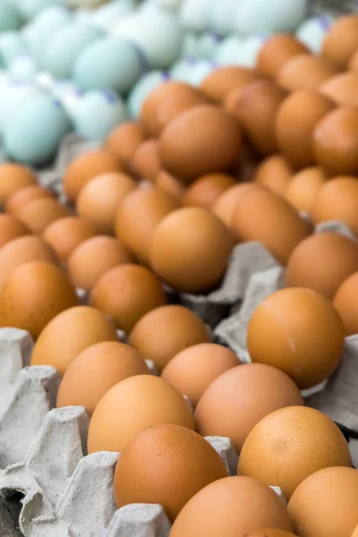 Pile of chicken eggs and duck eggs on a traditional market shelf display.
