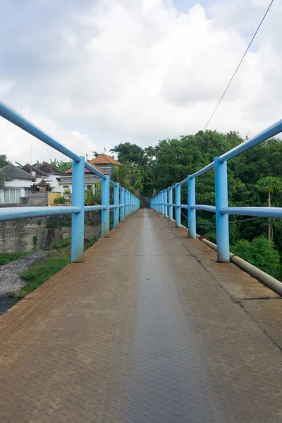 A small blue bridge made of iron. A small bridge connecting two villages.