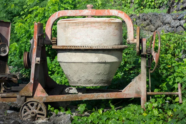 stock image A cement and concrete mixer is placed between the clay plants. Good illustration for construction tools concept