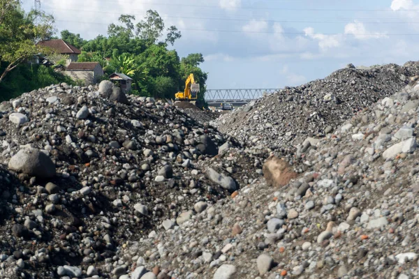 stock image Pile of sand and rocks in construction area and excavator at work transporting rocks. Good illustration for construction work concept