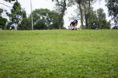 Anne ve kızı çimlerin üzerinde rahatça oturuyorlar. Anne ve çocuk konsepti için iyi bir illüstrasyon. negatif boşluk