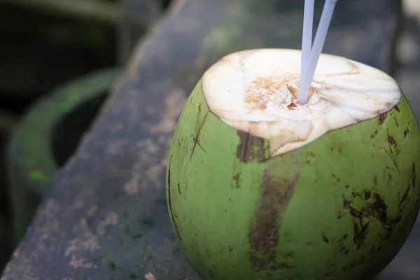 A young coconut is ready to drink with two straws in the middle