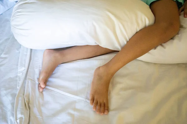 The little feet of a little girl hugging a pillow