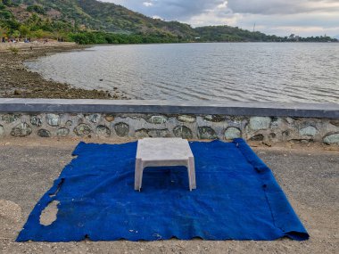 A plastic table with a mat on the beach. clipart