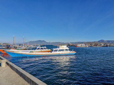Güneş doğarken kırsal bir rıhtımda demirlemiş geleneksel balıkçı teknelerinin manzarası sakin kıyı yaşamını yansıtıyor.