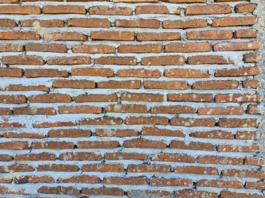 Düz olmayan çimento alçılı, kaba, tamamlanmamış dokusunu vurgulayan sert tuğla bir duvarın arka planı