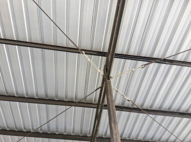 Metal çatı katının yakın görüntüsü destek kabloları ve kıvrımlı demir tavanı var.