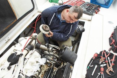 Tekne tamircisi gemi motorunu tamir ediyor.