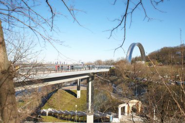 Kyiv, Ucraine-03.30.2023: Saint Volodymyr üzerinden Ukrayna 'nın başkenti Kyiv' e inen yaya ve bisiklet köprüsü. Glass Bridge, modern yaya köprüsü Kyiv 'in tarihi merkezini Arka Druzhby Narodiv' e bağlıyor.
