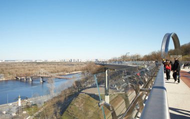Kyiv, Ucraine-03.30.2023: Saint Volodymyr üzerinden Ukrayna 'nın başkenti Kyiv' e inen yaya ve bisiklet köprüsü. Glass Bridge, modern yaya köprüsü Kyiv 'in tarihi merkezini Arka Druzhby Narodiv' e bağlıyor.