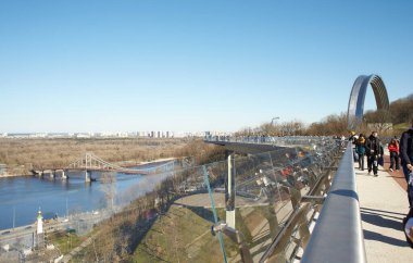 Kyiv, Ucraine-03.30.2023: Saint Volodymyr üzerinden Ukrayna 'nın başkenti Kyiv' e inen yaya ve bisiklet köprüsü. Glass Bridge, modern yaya köprüsü Kyiv 'in tarihi merkezini Arka Druzhby Narodiv' e bağlıyor.