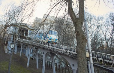 Yamaç boyunca uzanan raylarda mavi ve beyaz bir füniküler kablo yükselir. Füniküler tramvay, yan görüş. Kyiv İstasyonu, Ukrayna