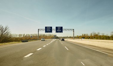 Otoyolda, İrlanda 'da arabaların arka manzarası. Metal güvenlik bariyeri ya da tırabzanı olan yol. Bulutlu mavi gökyüzünün altındaki asfaltta arabalar. Otoyol trafiği.