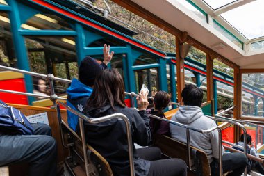 Kyoto, Japan - November 25, 2018: Passengers on open air train greeting other car passengers during travel on moutain slope to attraction point.