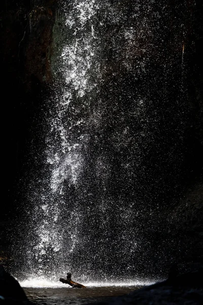 瀑布落在黑暗的洞穴背景的池塘上 — 图库照片