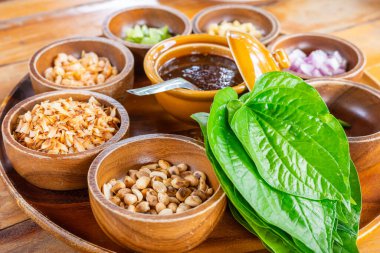 Yeşil betel yapraklı büyük bir tabak dolusu taze malzeme. Adı Miang Kham. Geleneksel Tayland aperatifi..
