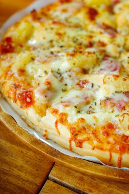 Ahşap masaya konan fırından elde edilen ev yapımı Hawaii pizzasına yakından odaklan.
