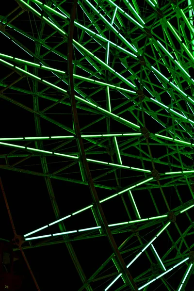 黑暗背景下摩天轮结构上的绿光荧光 — 图库照片