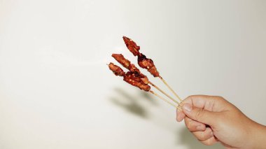 El, arka planda izole edilmiş kırmızı biberli bir çatal tutuyor..