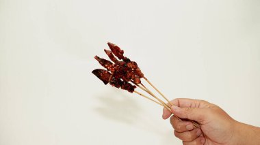 Beyaz arka planda mangalda tavuk eti var.