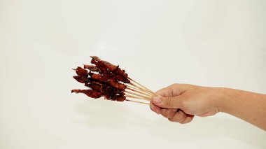 Kadın elleri beyaz arka planda barbekü yapıyor.