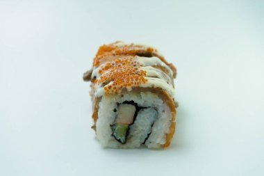 Suşi rulosunun yakın çekimi, üzerine sos serpilmiş ve tobiko serpiştirilmiş.