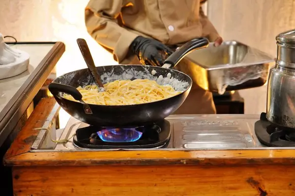 Spagetti Carbonara 'nın orta sıcaklıkta tavada pişirildiği fotoğraf.