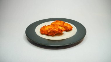 Beyaz arka planda siyah tabakta kızarmış tavuk kanadı.