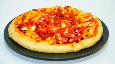 Tahta arka planda sosisli ve peynirli pizza.