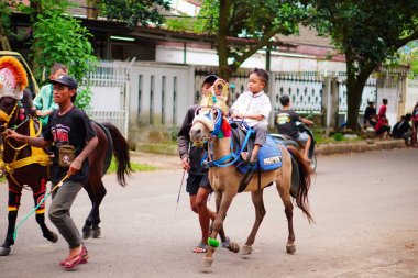 Sokak geçit töreninde midilliye binen bir çocuk. Kültürel etkinlik, gelenek ve topluluk kutlamaları.