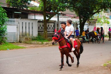 Bir idareciyle sokakta ata binen bir çocuk. Eğlenceli etkinlik.