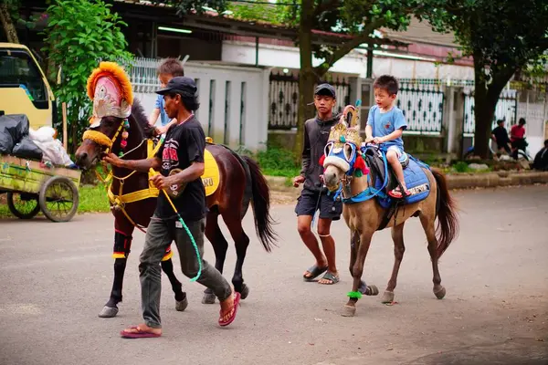 Endonezya 'da bir sokakta süslü midillilere binen çocuklar.