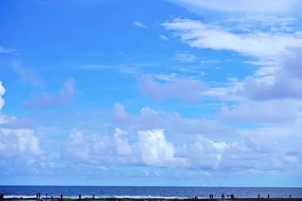 Mavi gökyüzü ve bulutlu okyanus manzarası.