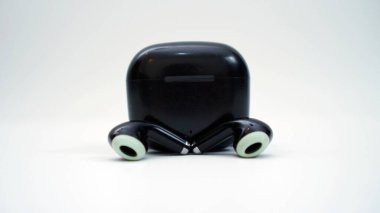 Kablosuz kulaklıklar ve beyaz arka planda şarj cihazı. Teknoloji ve müzik kavramı.