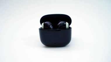 Beyaz arkaplanda şarj durumunda kablosuz kulaklıklar.