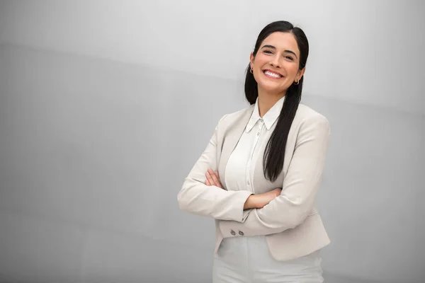 Beautiful hispanic business woman, executive, boss, CEO, entrepreneur in a suit, smiling and standing confidently with arms crossed