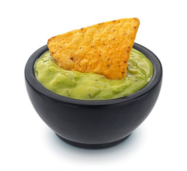 Guacamole, avokado sosu ve beyaz arka planda izole edilmiş mısır cipsi ile dolu bir kase.