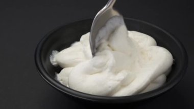 Bir kase krem peynirli kaşık, fotokopi alanı olan siyah arkaplan