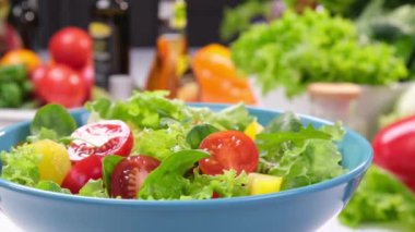Modern mutfak arka planında taze yaprak ve domates salatası, ticari video konsepti.