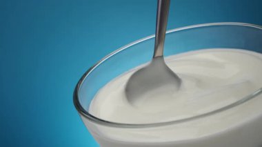 Bir kase ekşi krema ve kaşık, mavi arka plan ve fotokopi alanı