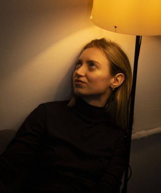 Modern bir dairenin içinde ışığı olan güzel bir sarışının portresi.